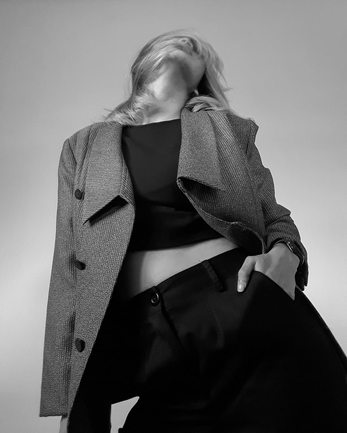Low-angle monochrome portrait of a model in a textured blazer and dark trousers